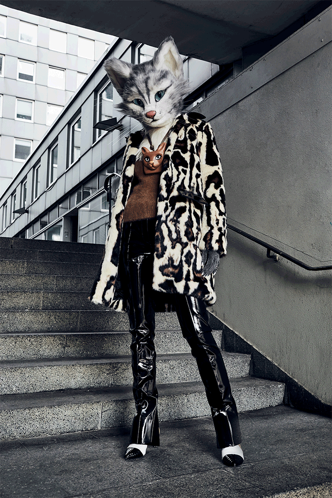 Modebloggerin Pheline von Fou de Pheline trägt ein Outfit mit den beiden Trendthemen Lack und Leopardenmuster. Das Outfit besteht aus einem Webpelzmantel mit Leopardenmuster von Carven, einem hellbraunem, flauschigen Wollpullover von Bally, einer schwarzen Lackhose von Barbara Bui, einer großen Halskette mit einem Katzenkopf aus Leder von Loewe und Schnür-Stiefeletten von Bally.