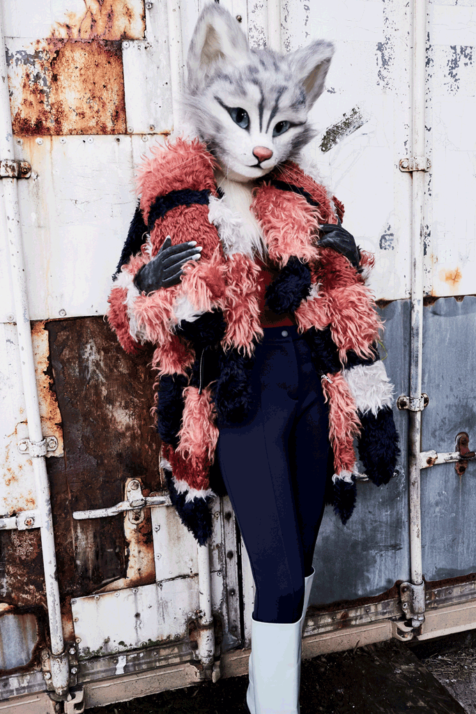 Katzenlady Pheline trägt eine gestreifte Flokati-Jacke samt Fake Fur-Fuchsstola von Tim Labenda, einen Rollkragenpullover von Acne Studios, eine Steghose von Fendi und Stiefel von Hermès.