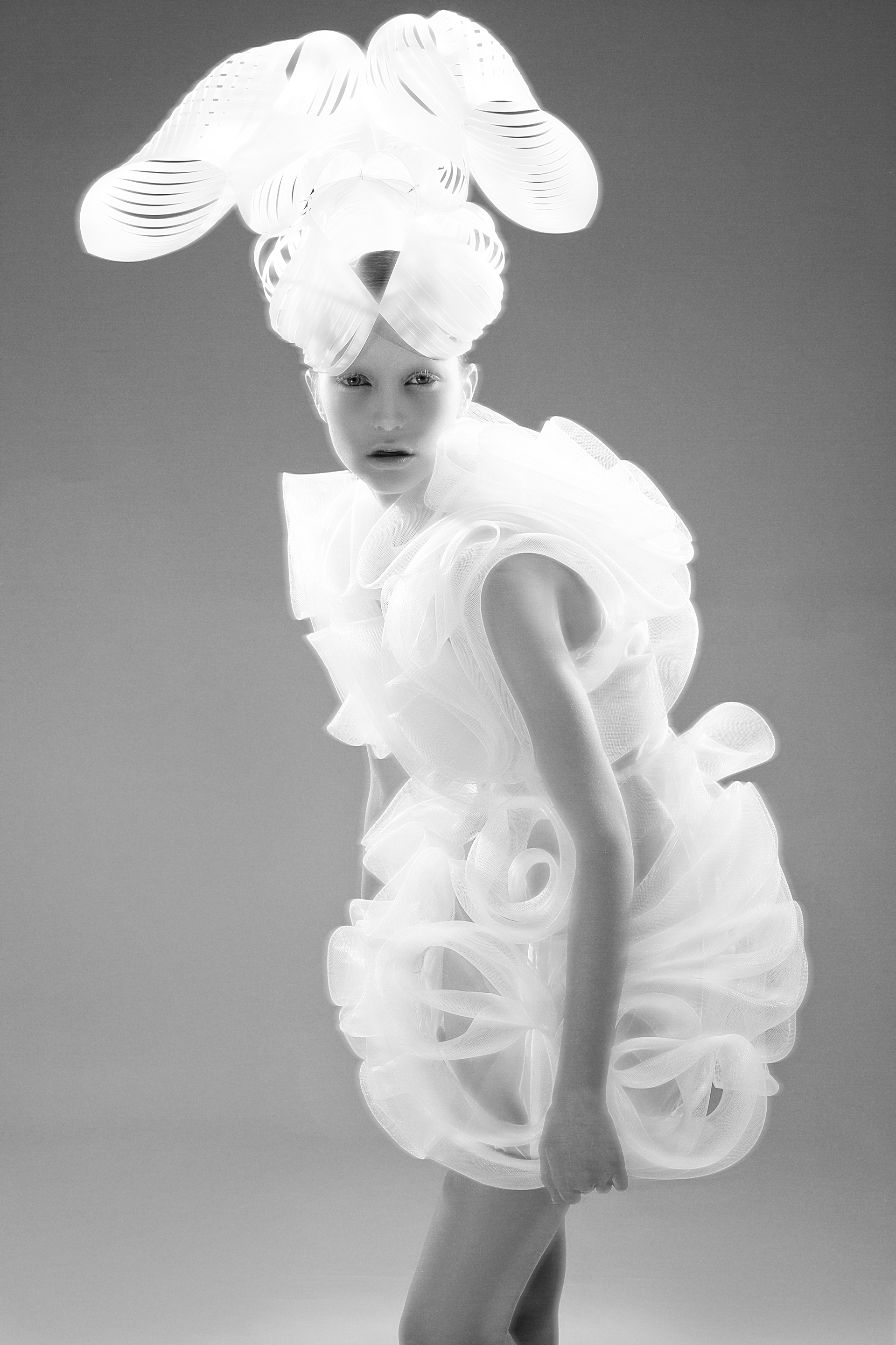 Auf der Modefotogarfie ist einen Model einem weißen, sklupturalen Kleid zu sehen. Auf dem Kopf trägt das Mädchen einen ausladenden, weißen Hut. Designer: Tanel Veenre. Foto: Woland. Buch: Otherworldly. © Gestalten 2016