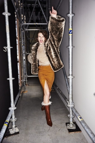 Ein Model im Backstagebereich der Marni Herbst/Winter 2017 Modenschau trägt eine glänzende Fake Fur Jacke und einen hoch geschlitzten Pencilskirt.