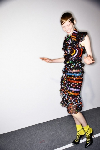Dieses Bild zeigt ein Model Backstage bei der Givenchy Frühjahr/Sommer 2017 Show. Es trägt ein Rüschenkleid mit bunten Streifen und Punkten.