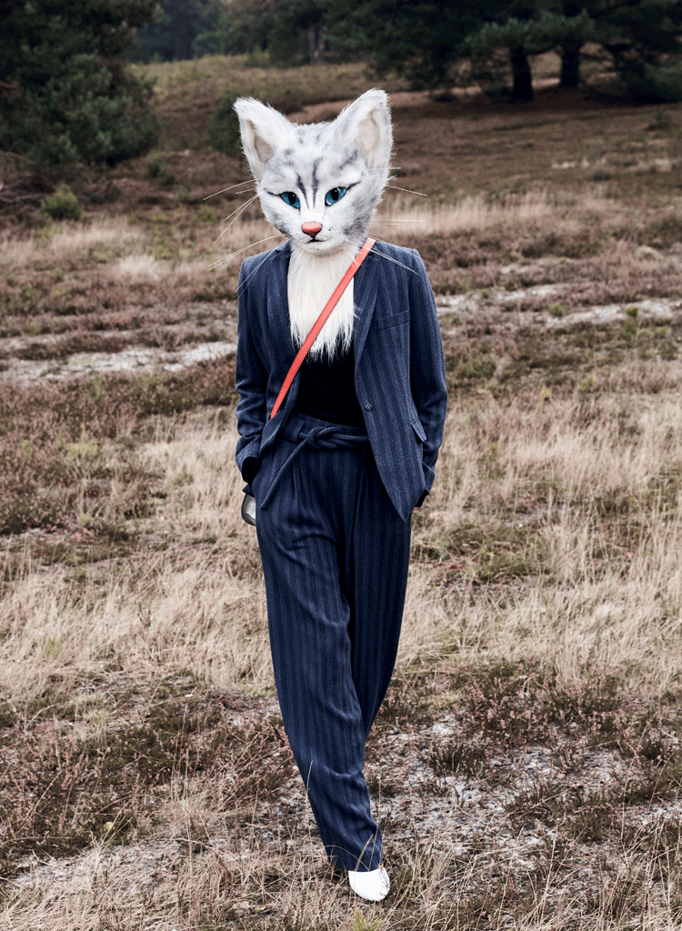 Auf den Fotos ist Katzenlady Pheline in der Fischbeker Heide bei Hamburg zu sehen. Sie trägt einen blauen Hosenanzug und kombiniert dazu einen schwarzen Pullover. Beides stammt von der Designerin Kathrin Musswessels. Außerdem trägt sie eine rot-graue Crossover-Bag von Bree und weiße Booties von Hermès.