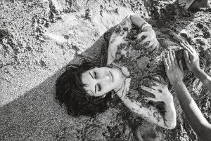 2009 lässt sich Amy Winehouse entspannt und ausgelassen von ihrem Patenkind am Cariblue Beach in Saint Lucia mit Sand bedecken.